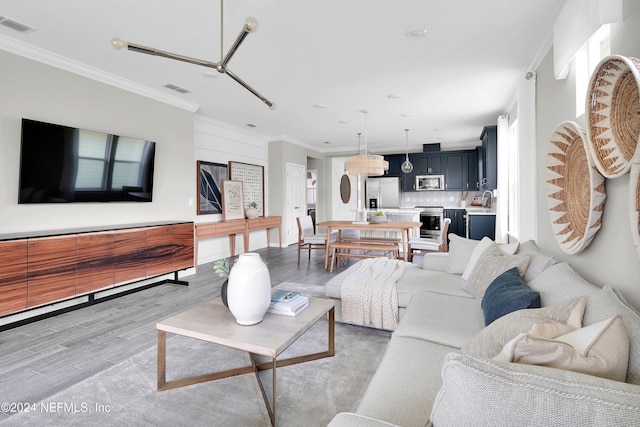 living room with visible vents, crown molding, and light wood-style flooring