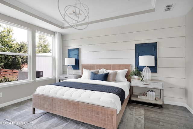 bedroom with visible vents, wood finished floors, a tray ceiling, crown molding, and a chandelier