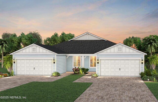 view of front facade with a yard, board and batten siding, an attached garage, and roof with shingles