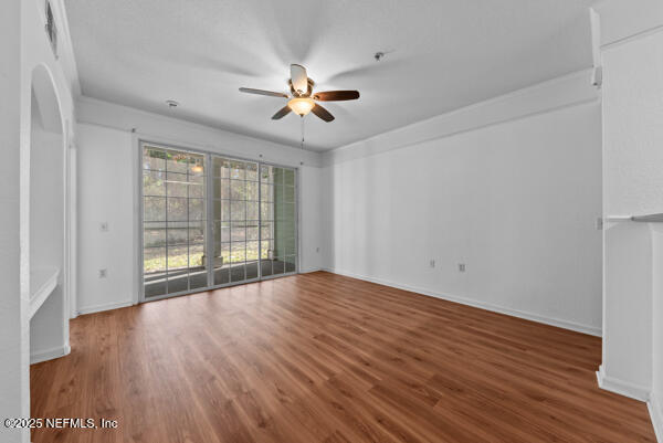 unfurnished living room with ceiling fan, baseboards, and wood finished floors