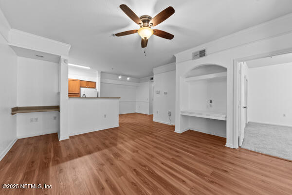 unfurnished living room featuring ceiling fan, wood finished floors, visible vents, and baseboards