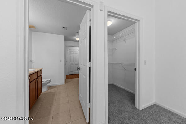 bathroom featuring visible vents, toilet, vanity, baseboards, and tile patterned floors