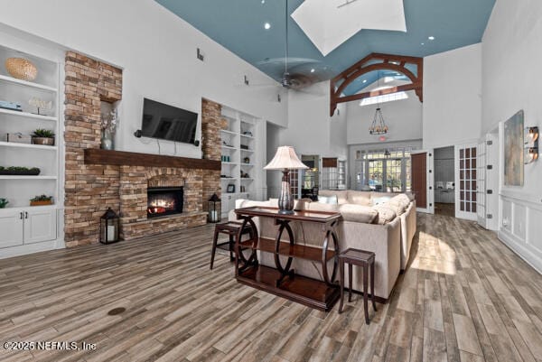 living area with built in shelves, a fireplace, and wood finished floors