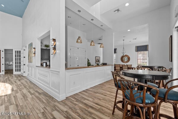 dining room with recessed lighting, visible vents, light wood-style flooring, and a high ceiling