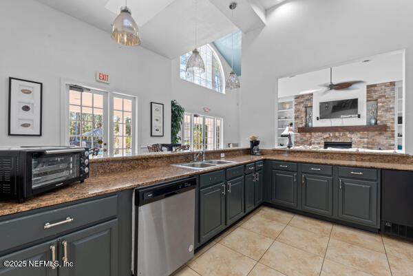 kitchen with light tile patterned floors, a toaster, a sink, dishwasher, and dark countertops