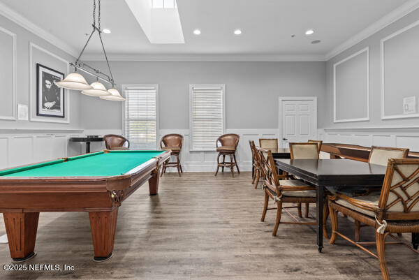 rec room featuring ornamental molding, a decorative wall, wood finished floors, and recessed lighting