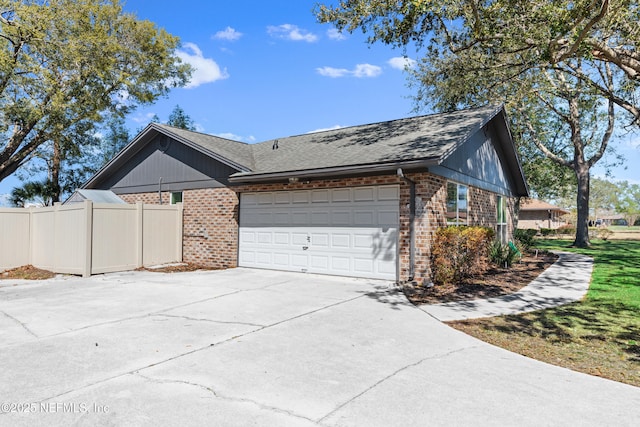 view of property exterior with brick siding, roof with shingles, concrete driveway, an attached garage, and fence