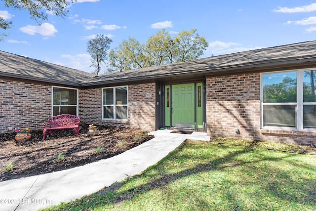 doorway to property featuring a yard and brick siding