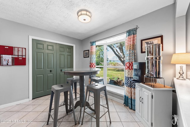 dining space featuring light tile patterned floors, baseboards, and a textured ceiling