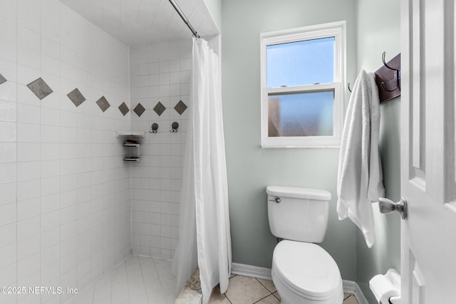 bathroom featuring tile patterned flooring, baseboards, tiled shower, and toilet