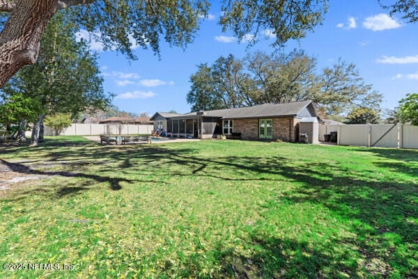 view of yard with a fenced backyard and a sunroom