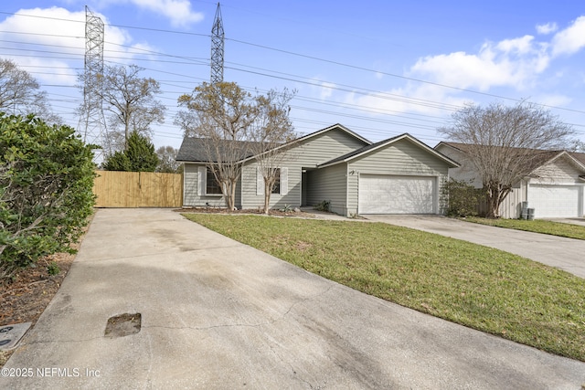 view of front of house featuring a garage, concrete driveway, a gate, fence, and a front lawn