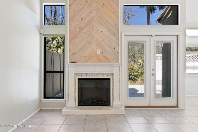 unfurnished living room featuring french doors, a high ceiling, a healthy amount of sunlight, and a glass covered fireplace