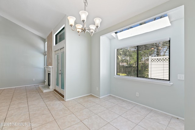 spare room featuring baseboards, a notable chandelier, light tile patterned flooring, and vaulted ceiling with skylight