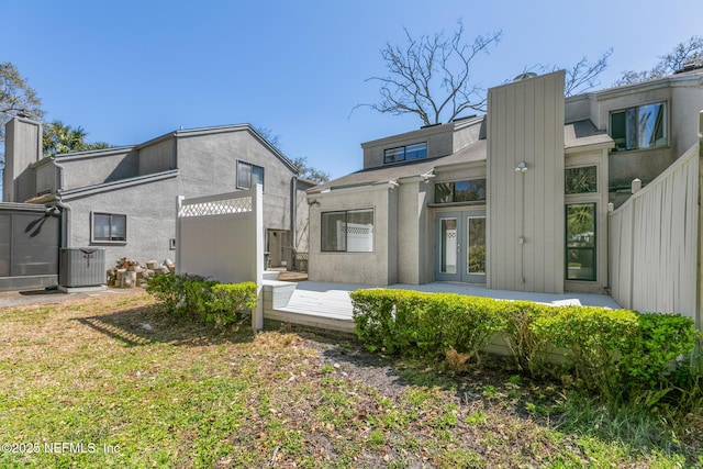 back of property featuring stucco siding, french doors, central AC, and fence