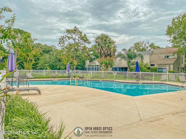 pool with a patio area and fence