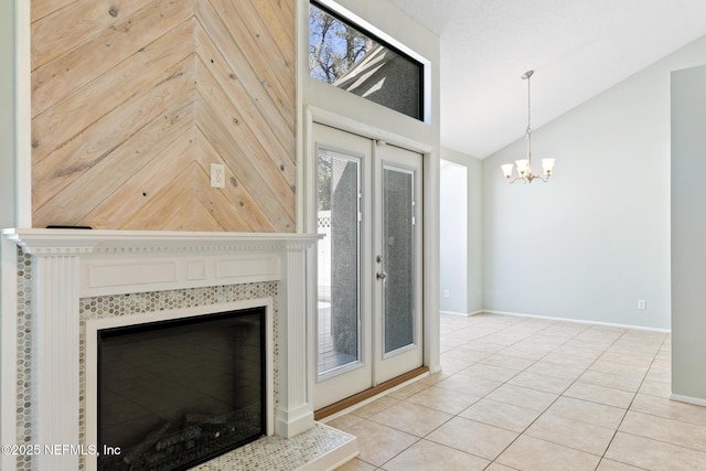 unfurnished living room with baseboards, lofted ceiling, light tile patterned flooring, a tiled fireplace, and a chandelier