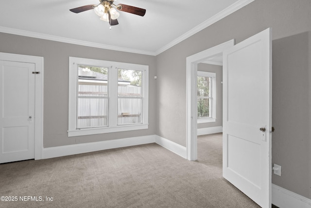 spare room with ornamental molding, carpet, ceiling fan, and baseboards