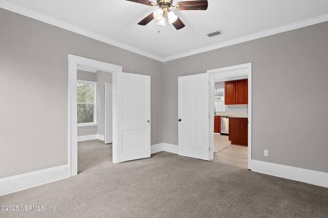 unfurnished bedroom featuring baseboards, visible vents, light colored carpet, ceiling fan, and ornamental molding