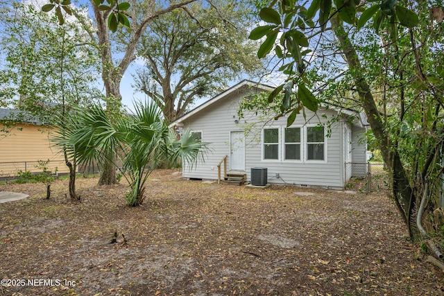 rear view of property featuring entry steps, crawl space, fence, and central air condition unit