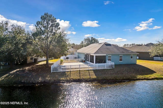 rear view of house with a patio area, a lawn, a fenced backyard, and a water view