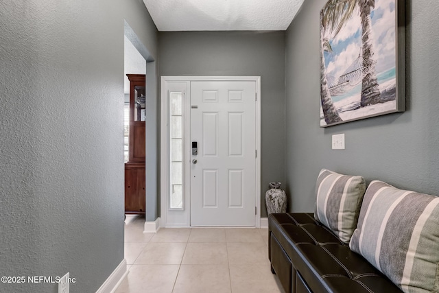 foyer featuring light tile patterned floors, baseboards, and a textured wall