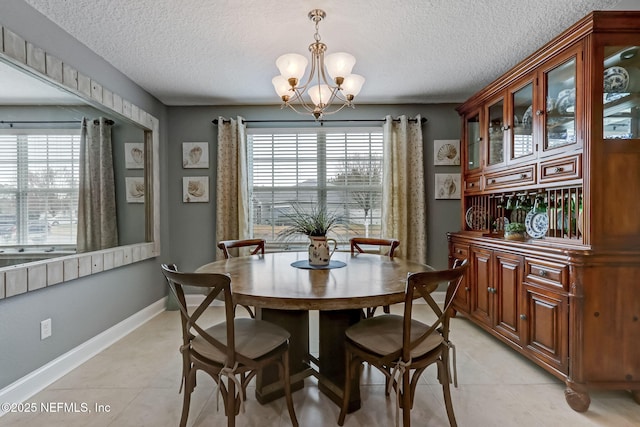 dining space with light tile patterned floors, a notable chandelier, a textured ceiling, and baseboards