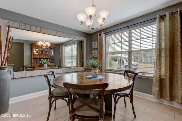 dining room with light tile patterned floors, baseboards, a textured ceiling, and an inviting chandelier