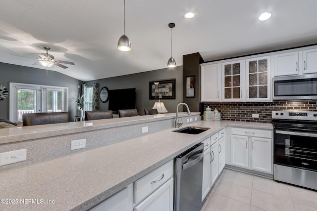 kitchen featuring decorative backsplash, open floor plan, appliances with stainless steel finishes, and a sink