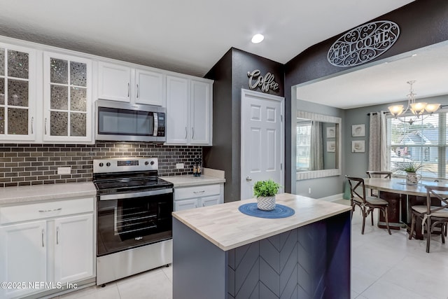 kitchen with glass insert cabinets, tasteful backsplash, appliances with stainless steel finishes, and white cabinets