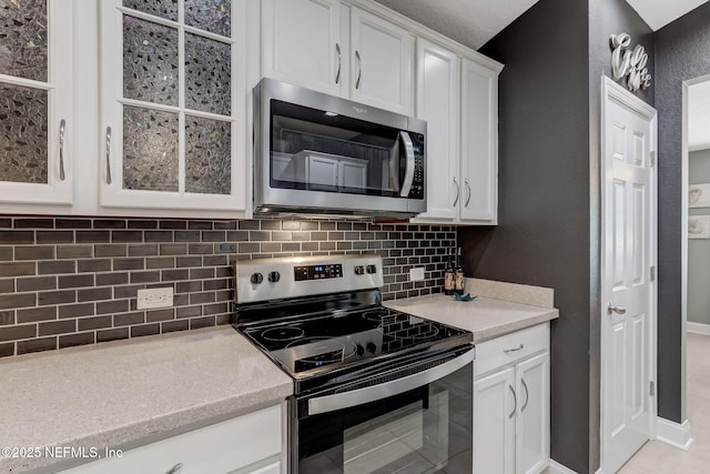 kitchen with baseboards, stainless steel appliances, light countertops, white cabinetry, and tasteful backsplash