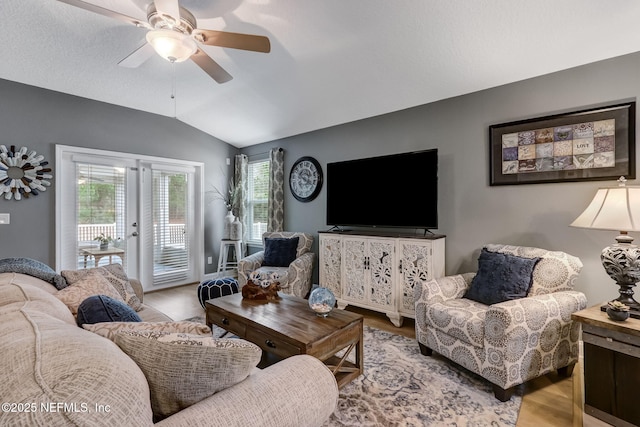 living room featuring a ceiling fan, vaulted ceiling, wood finished floors, and french doors