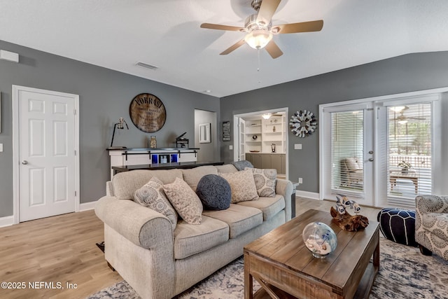 living room featuring baseboards, visible vents, light wood finished floors, and ceiling fan