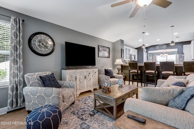 living room with baseboards, light wood finished floors, lofted ceiling, recessed lighting, and ceiling fan with notable chandelier