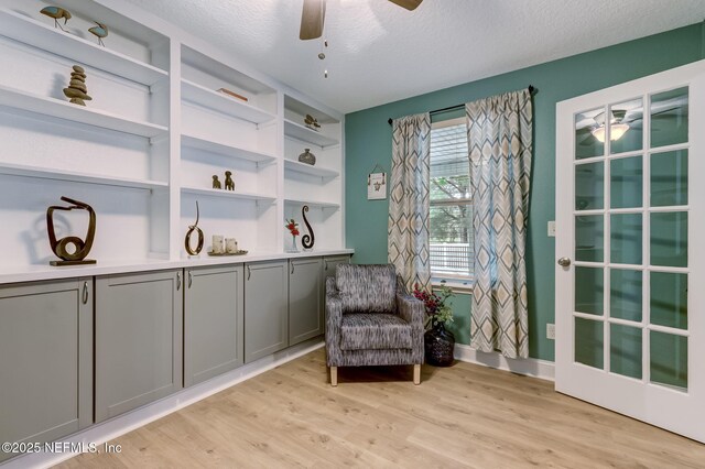 sitting room with a textured ceiling, light wood-type flooring, and ceiling fan