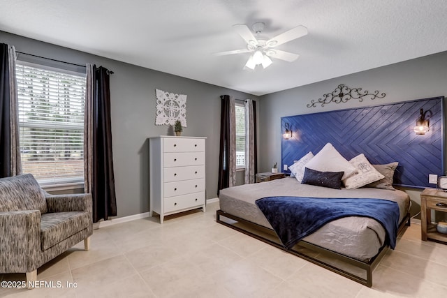 bedroom featuring baseboards, light tile patterned flooring, and a ceiling fan