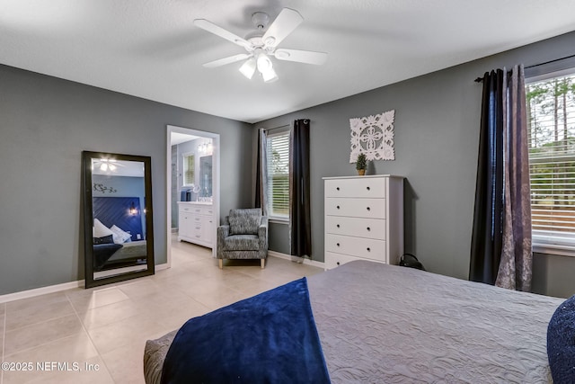 bedroom with light tile patterned floors, a ceiling fan, baseboards, and connected bathroom