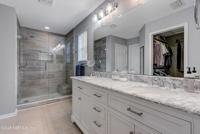 full bath with a shower stall, double vanity, visible vents, and a sink