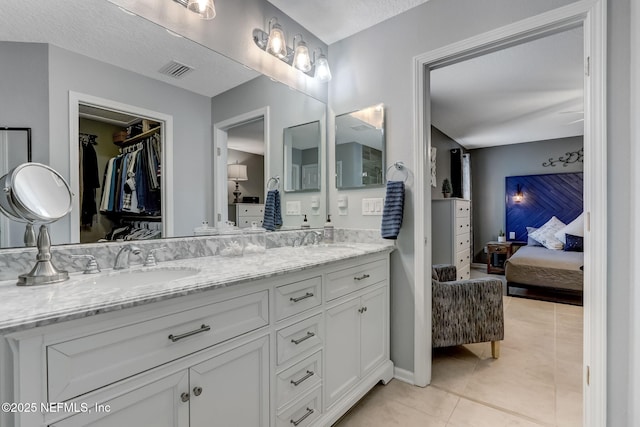 full bathroom with visible vents, double vanity, a sink, tile patterned floors, and connected bathroom