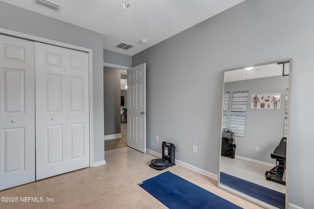 workout area featuring light tile patterned floors, visible vents, and baseboards