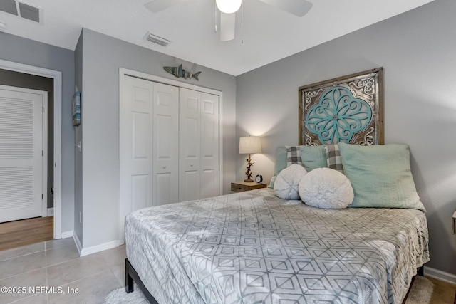 tiled bedroom with a ceiling fan, visible vents, a closet, and baseboards