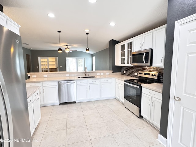 kitchen featuring light countertops, a peninsula, light tile patterned flooring, stainless steel appliances, and a sink