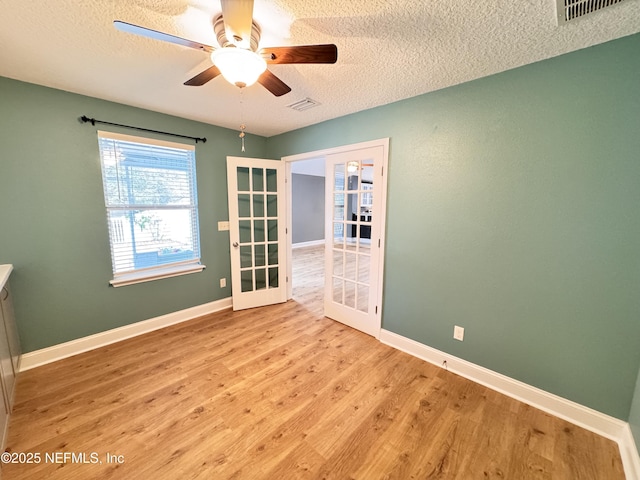 spare room featuring visible vents, french doors, baseboards, and wood finished floors