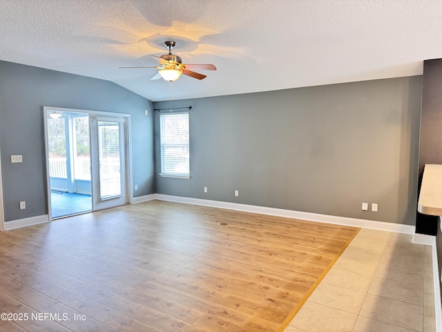 spare room with a textured ceiling, vaulted ceiling, light wood finished floors, and ceiling fan