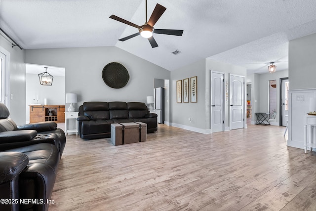 living room with visible vents, vaulted ceiling, a textured ceiling, ceiling fan, and light wood-type flooring