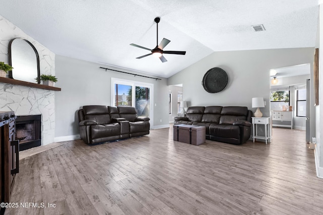 living room with lofted ceiling, a fireplace, visible vents, and wood finished floors