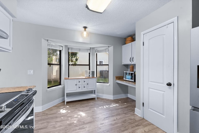 kitchen with light wood-type flooring, stainless steel microwave, plenty of natural light, and built in study area