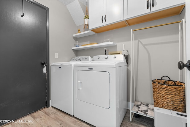 laundry area featuring light wood-style floors, washer and dryer, cabinet space, and a textured ceiling