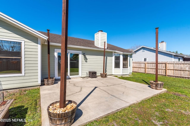 rear view of property featuring a patio, a yard, a chimney, and fence