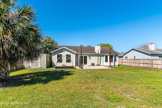 back of house featuring a storage shed, a patio, a fenced backyard, an outbuilding, and a yard